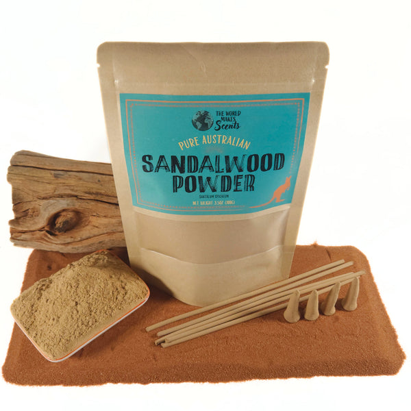 Bag of sandalwood powder with a spoonful of powder and wooden sticks on a brown mat.