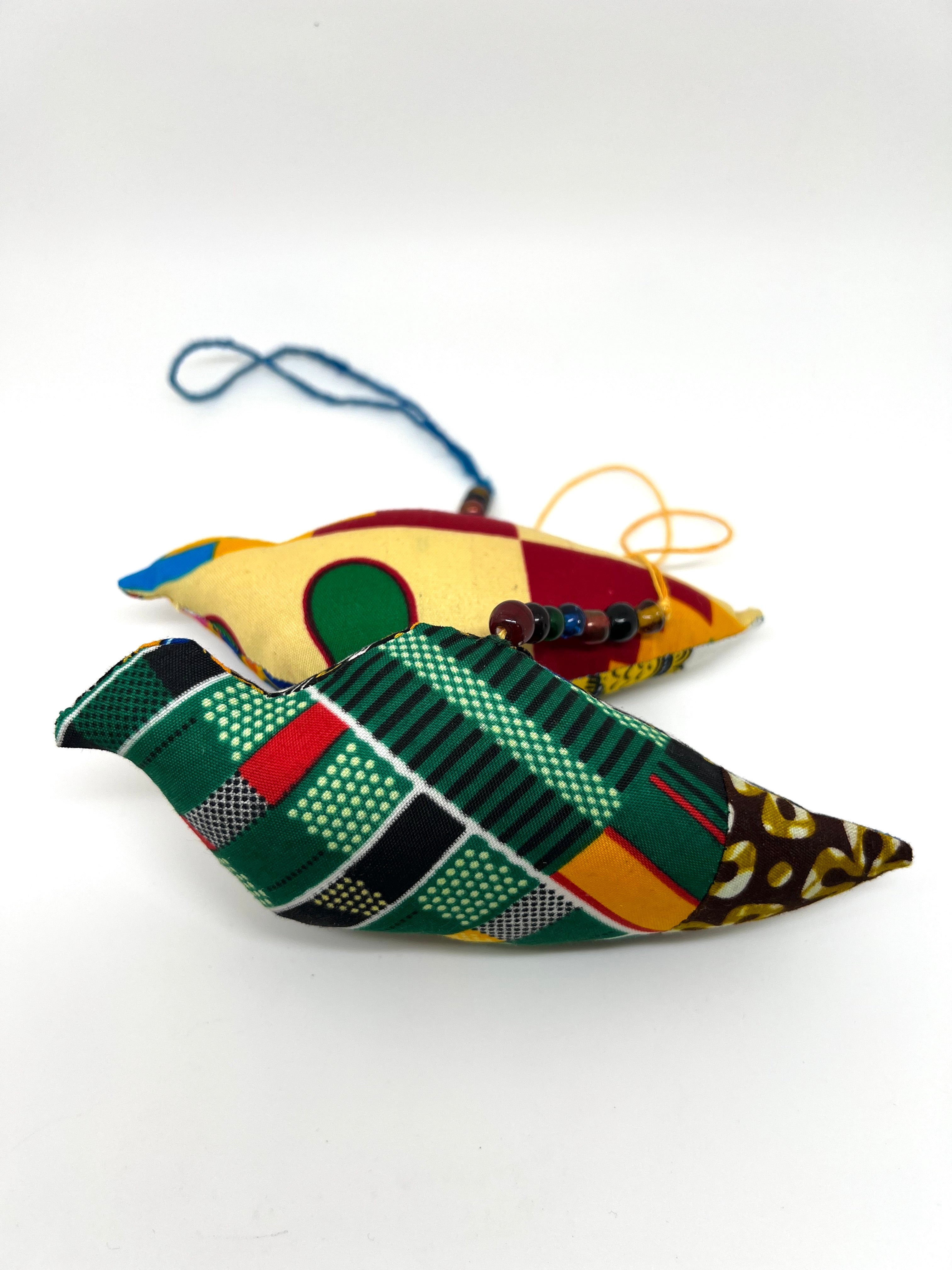 Two handmade African wax print patchwork ornaments showing varied fabric patterns front and back