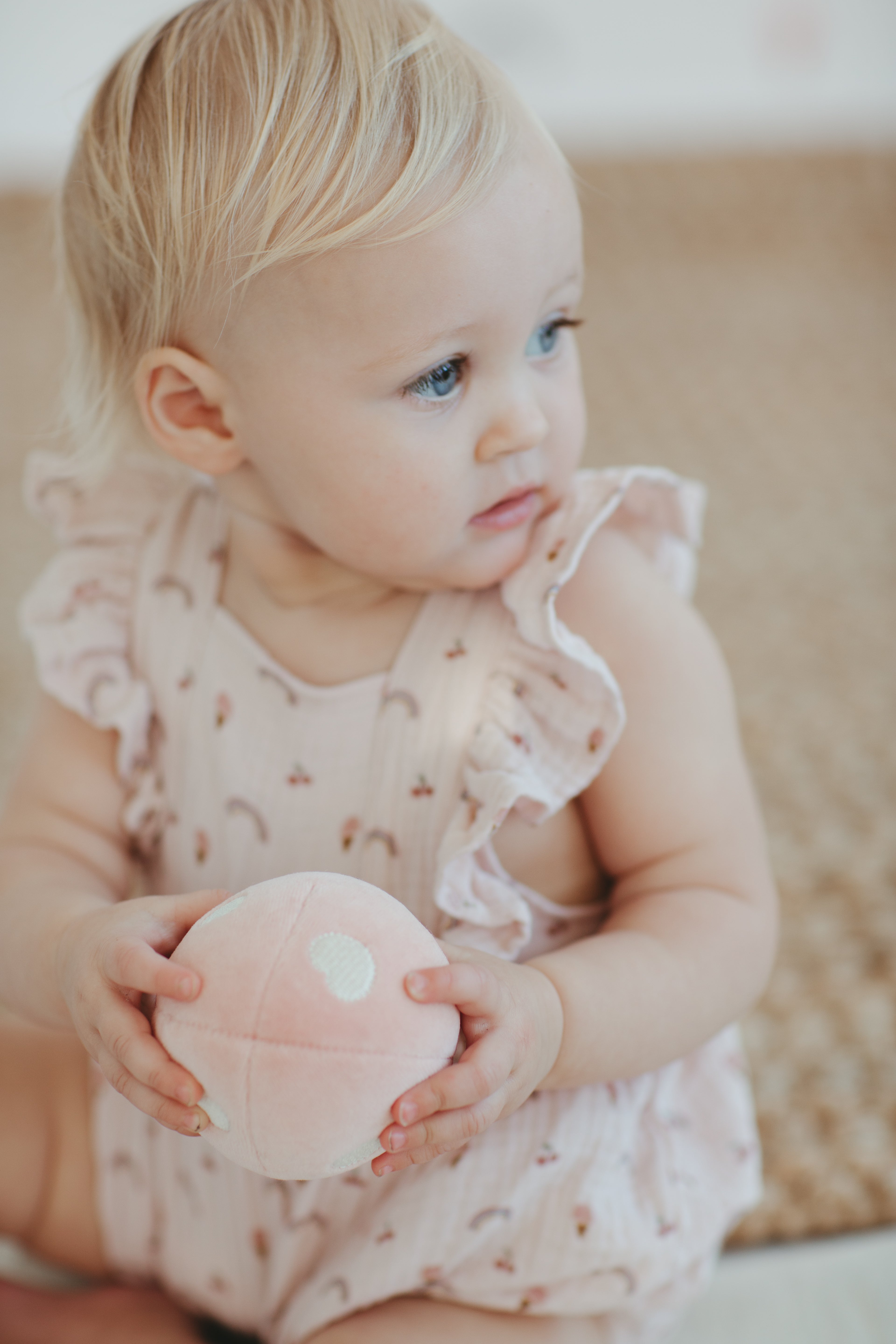 Apple Park rainbows and ice cream organic muslin baby romper displayed with mushroom rattles