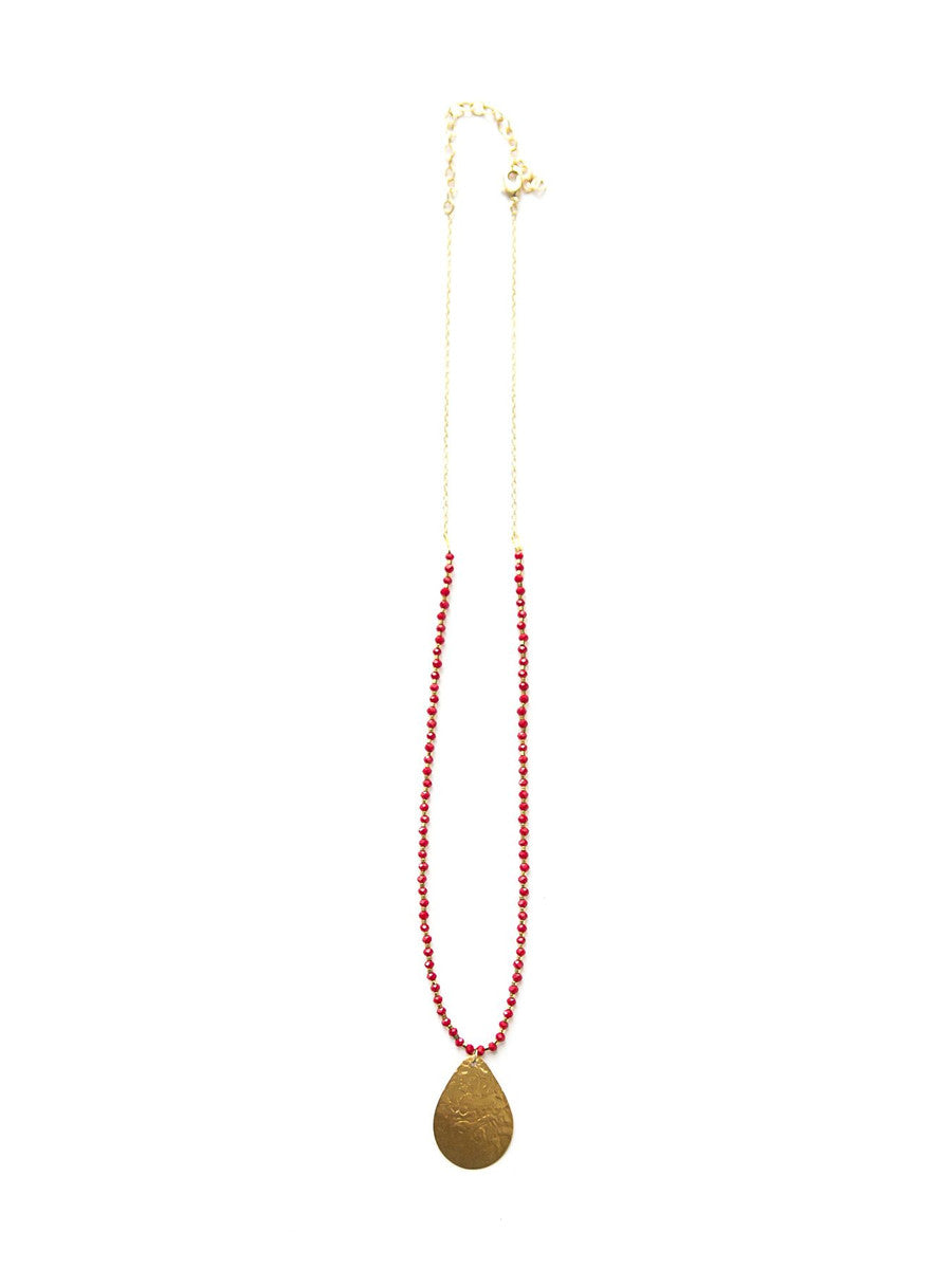 Detail shot of red glass beads and brass pendant necklace by Fair Anita