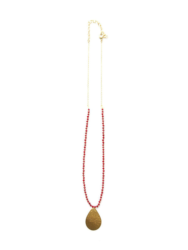 Detail shot of red glass beads and brass pendant necklace by Fair Anita