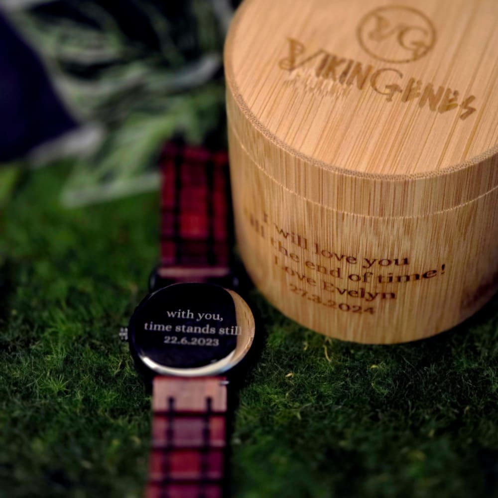 A wooden watch with a black dial and brown strap, displayed on a natural wood surface.