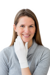 Woman wearing a gray sweater and white gloves on a white background. Remedywear adult eczema & psoriasis gloves with TENCEL & zinc oxide — dermatologist recommended, Oeko-Tex certified & made in Portugal. Heal dry, itchy hands. Shop now.
