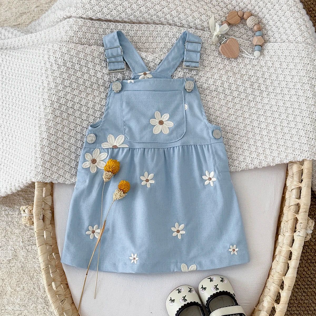 Blue denim dress with floral embroidery on a textured surface