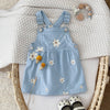Blue denim dress with floral embroidery on a textured surface