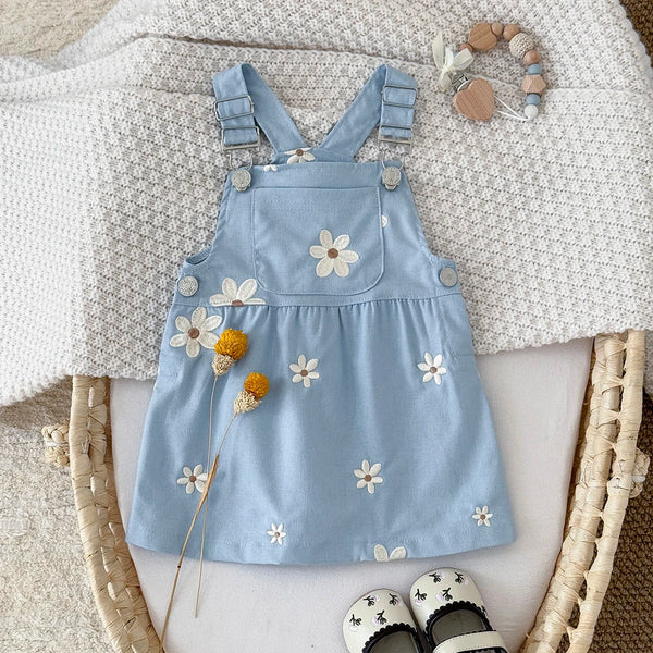 Blue denim dress with floral embroidery on a textured surface