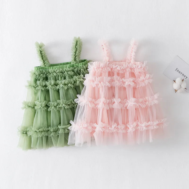 Two children's dresses, one green and one pink, on a white background.