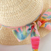 Close-up of a woven straw hat with a colorful satin ribbon tied in a bow around the crown.