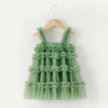 Green ruffled dress on a wooden hanger against a white background