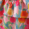 Close-up of a tiered ruffle skirt featuring a colorful watercolor tulip print in pink, orange, yellow, and green.