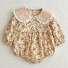 Floral baby romper with lace collar on a light background