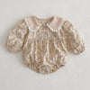 Floral baby romper with lace collar on a light gray background