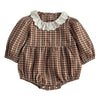 A baby romper with a brown and beige gingham pattern, featuring a white eyelet lace collar and a gathered ruffle waist, laid flat on a textured white background.