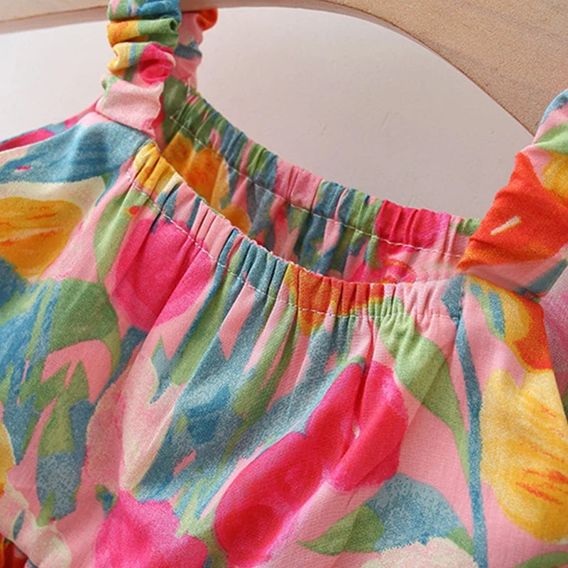 A close-up of a colorful floral-patterned top with a gathered elastic neckline, featuring pink, yellow, green, and blue tones.