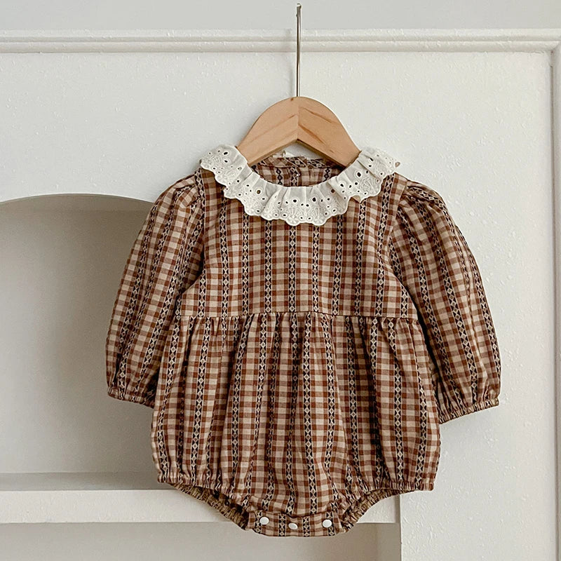 Close-up of the checkered print and lace collar on the baby romper