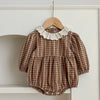 Close-up of the checkered print and lace collar on the baby romper