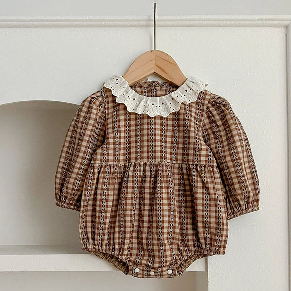 Close-up of the checkered print and lace collar on the baby romper