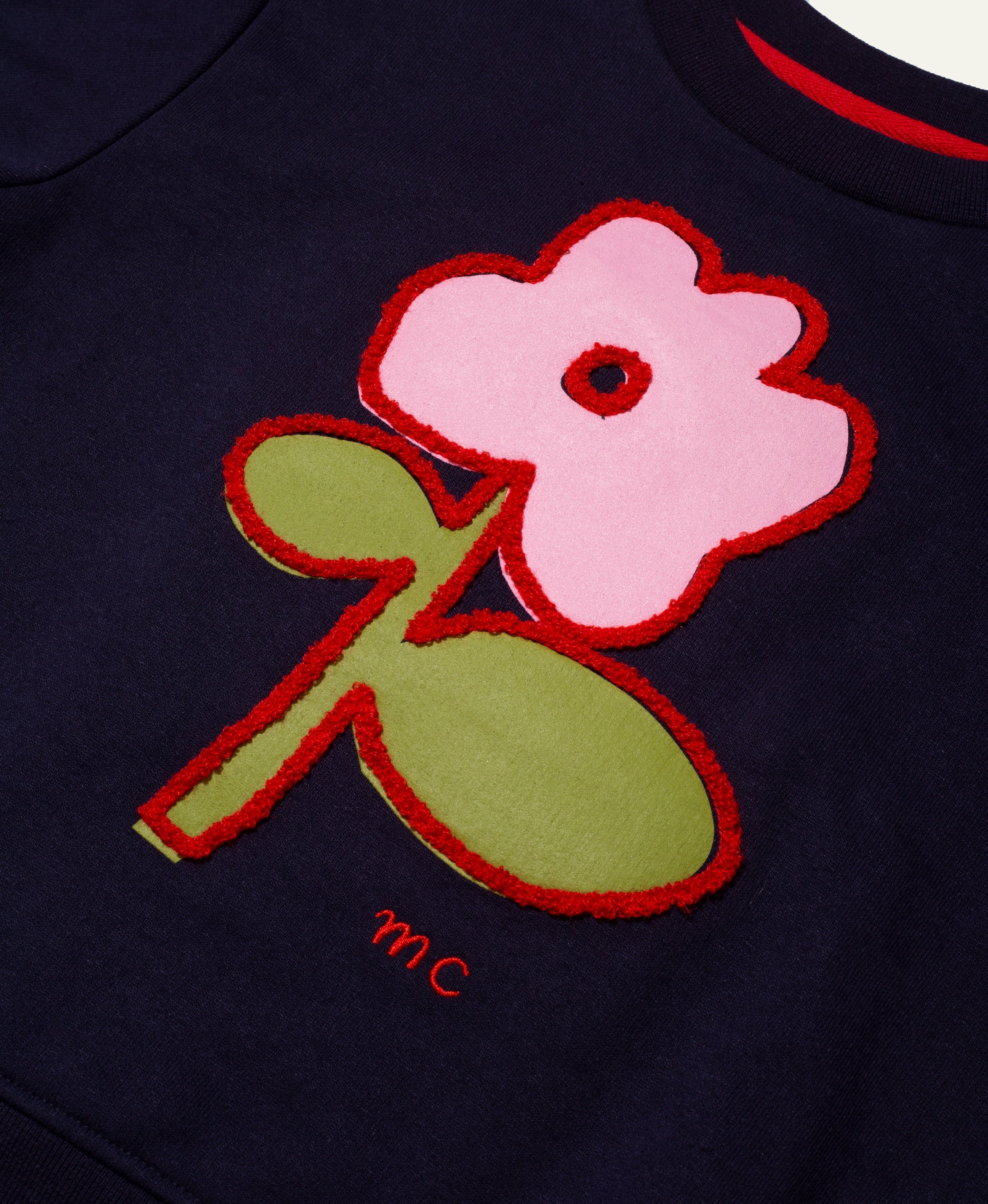 Navy blue shirt with pink flower and green leaf design on a dark background