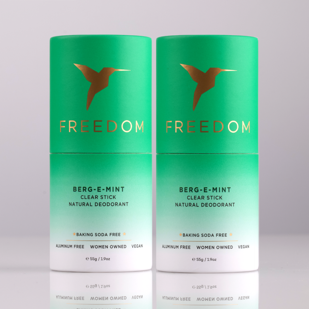 Two green 'Freedom' deodorant sticks on a light gray background