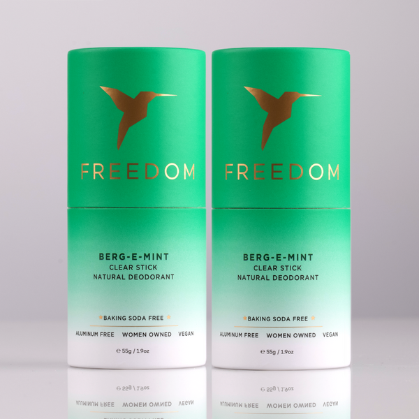 Two green 'Freedom' deodorant sticks on a light gray background
