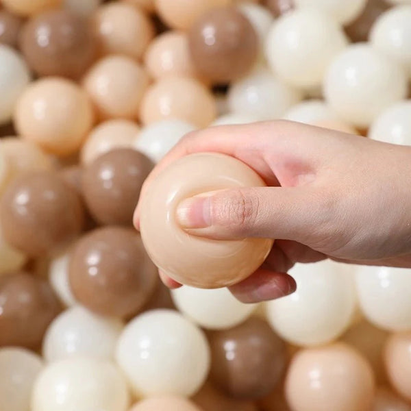 Hand holding a beige ball amidst a pile of similar balls