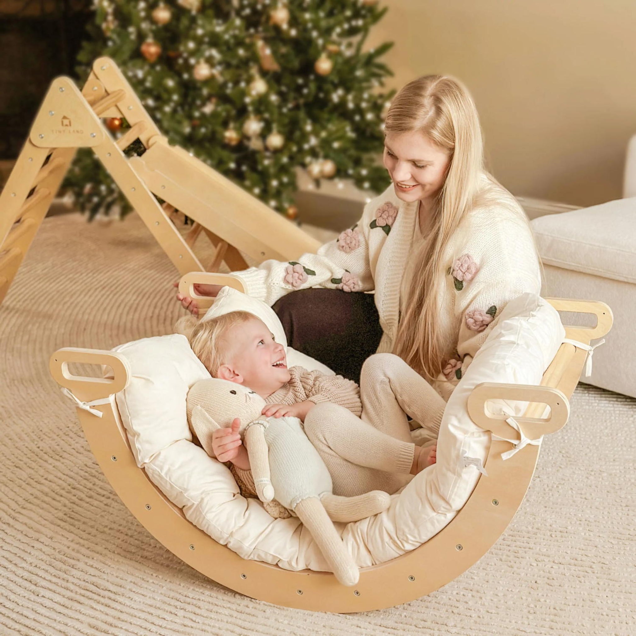 Woman and child in a wooden rocking chair with a Christmas tree in the background