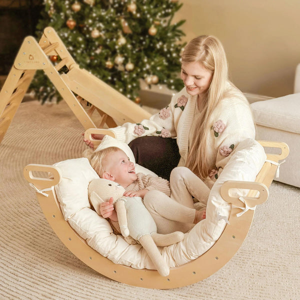 Woman and child in a wooden rocking chair with a Christmas tree in the background