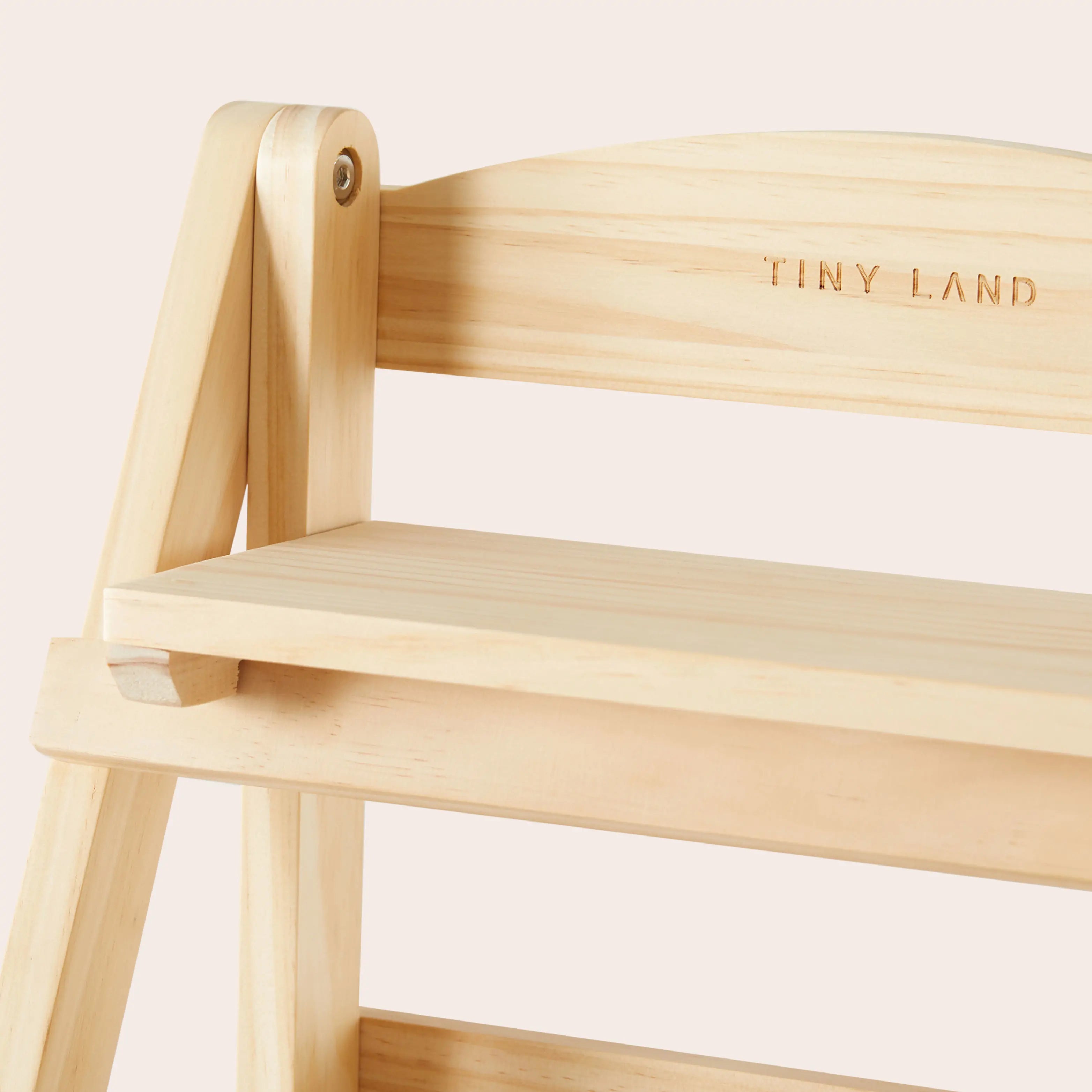 Wooden chair with 'TINY LAND' branding on a light pink background