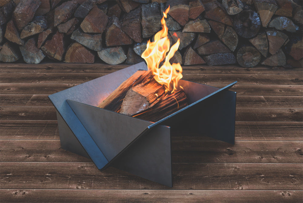 Metal fire pit with flames against a stone wall