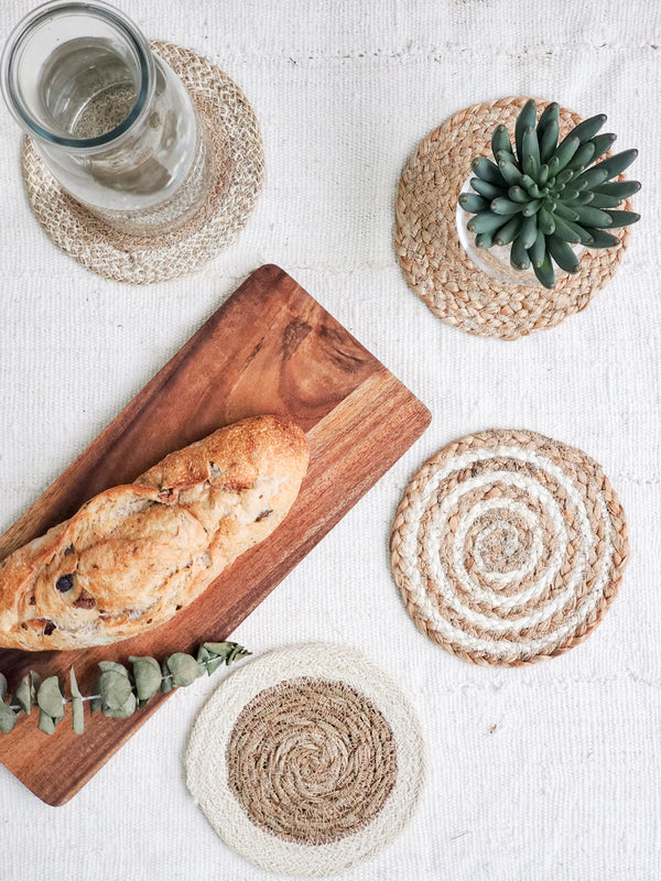 Rattan coasters with a loaf of bread and a glass on a white surface