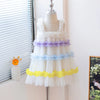 White dress with colorful ruffled layers on a mannequin against a white wall.