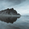 Mountain reflected in water under a cloudy sky
