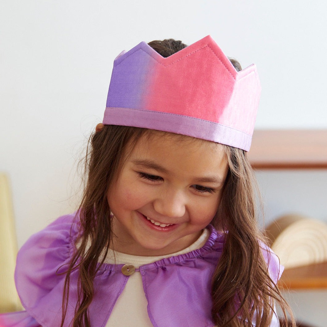 Child wearing a colorful paper crown with a plain background