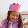 Child wearing a colorful paper crown with a plain background
