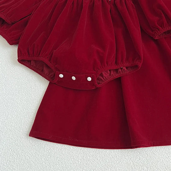 Red baby romper with white buttons on a textured white background