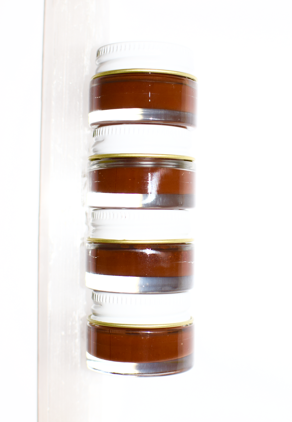 Stack of brown jars with white lids on a white background