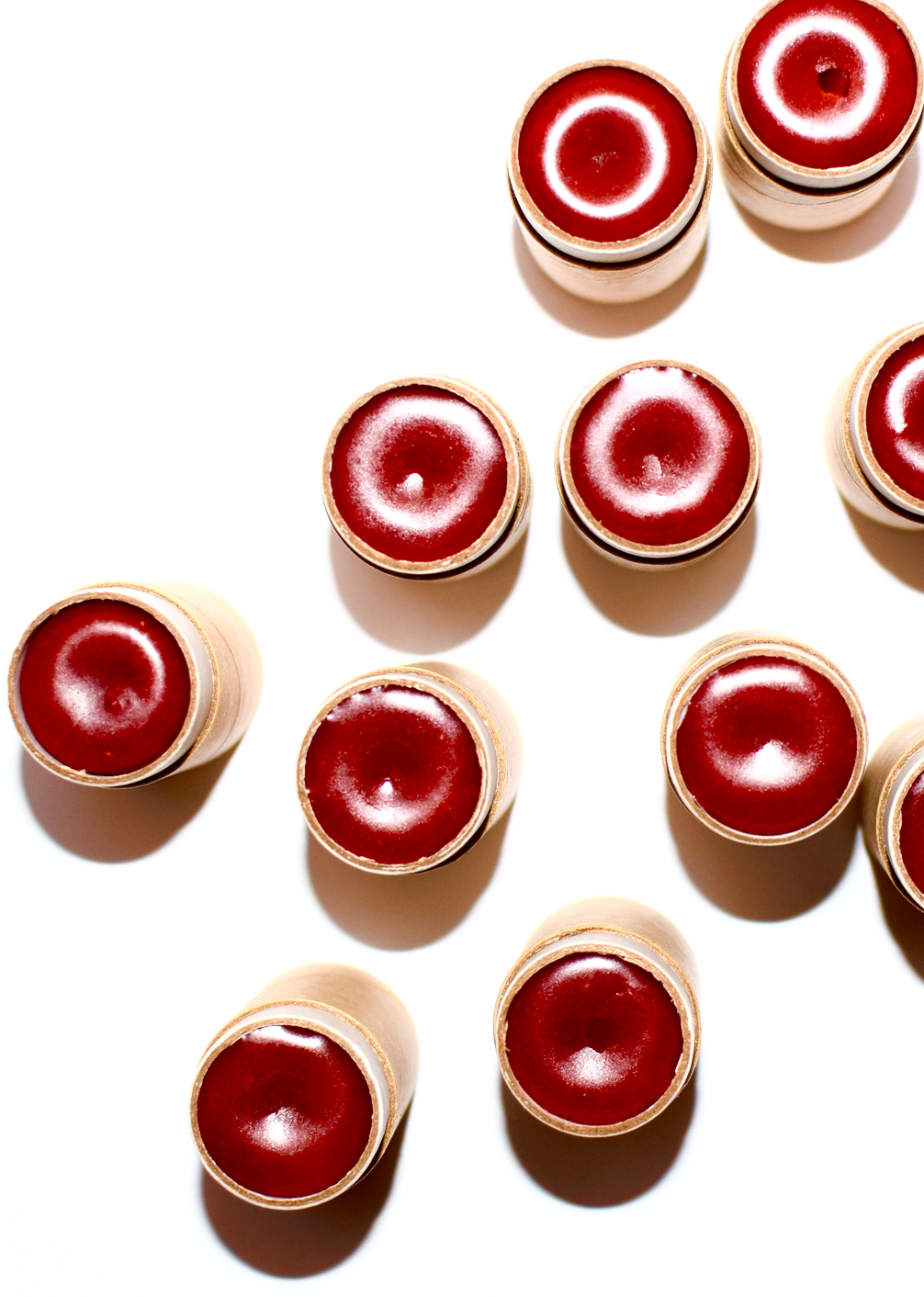 Red lip glosses with gold applicators on a white background