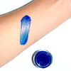 Blue spirulina tinted gloss swatched on a person's arm with the plant makeup glass jar shown below