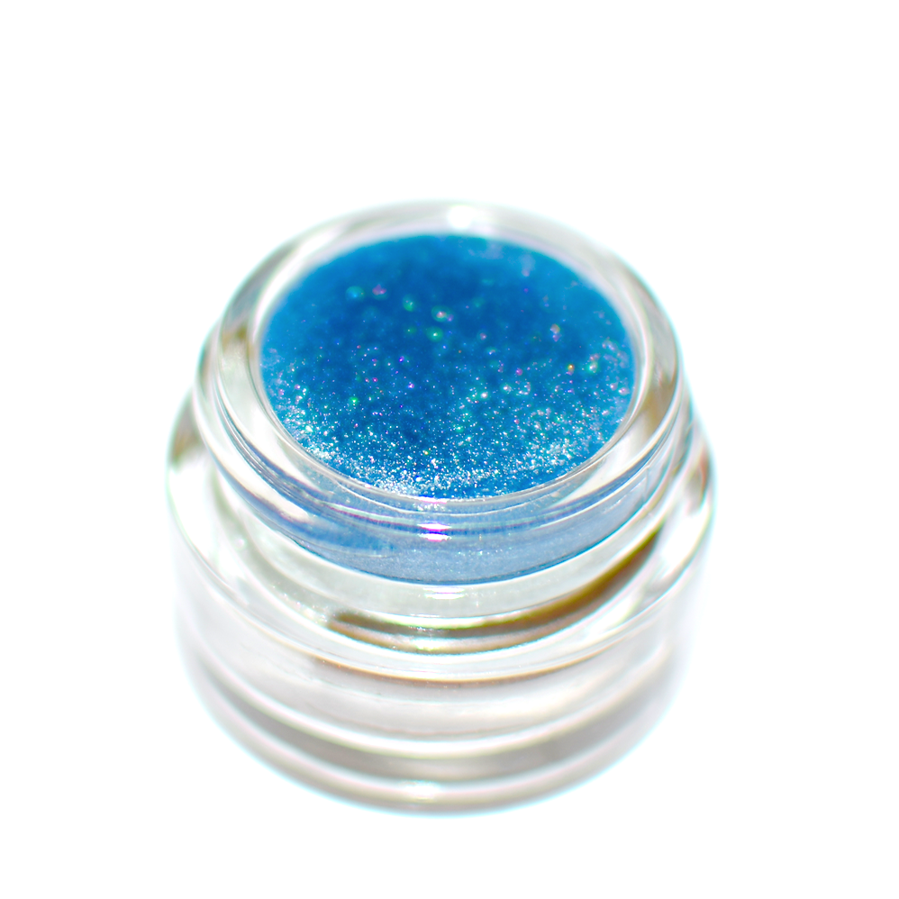 Small jar of blue glitter on a white background