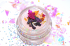 Small jar with colorful dried flowers on a multicolored confetti background