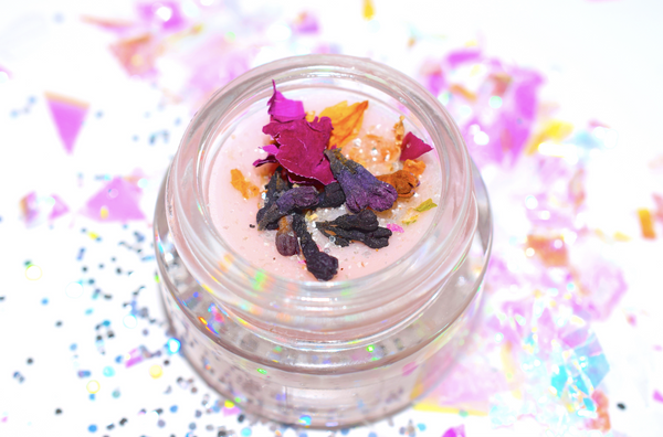 Small jar with colorful dried flowers on a multicolored confetti background
