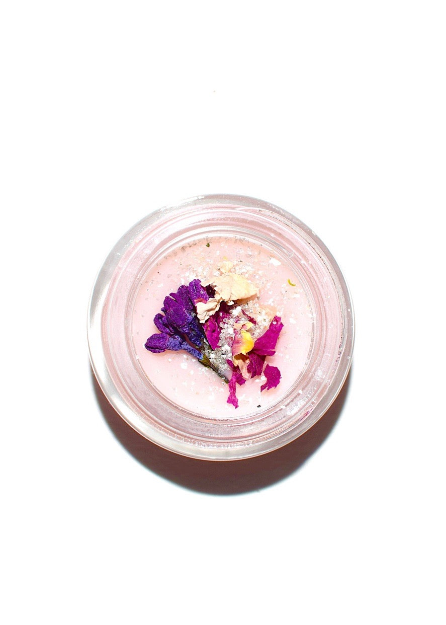 Small container with pink powder and colorful flowers on a white background