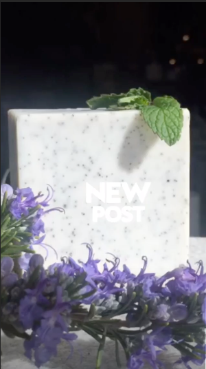White soap bar with green leaf on top surrounded by purple flowers