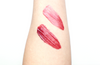 Two pink lipstick swatches on a person's arm against a white background
