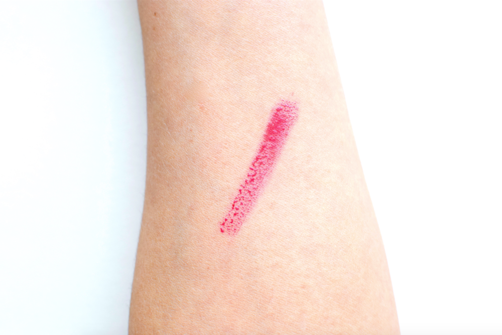 Pink lipstick swatch on a person's arm against a white background