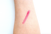 Pink lipstick swatch on a person's arm against a white background
