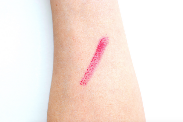 Pink lipstick swatch on a person's arm against a white background