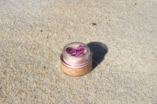 Small jar with pink lid on sandy surface