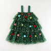 A green tulle Christmas tree skirt dress for toddlers, featuring a tiered design decorated with gold sequin stars and colorful pom-pom ornaments, complete with matching green shoulder straps.