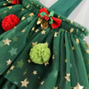 A close-up of a green tulle skirt decorated with gold star patterns, a red and green bow, gold bells, and fabric pom-poms.